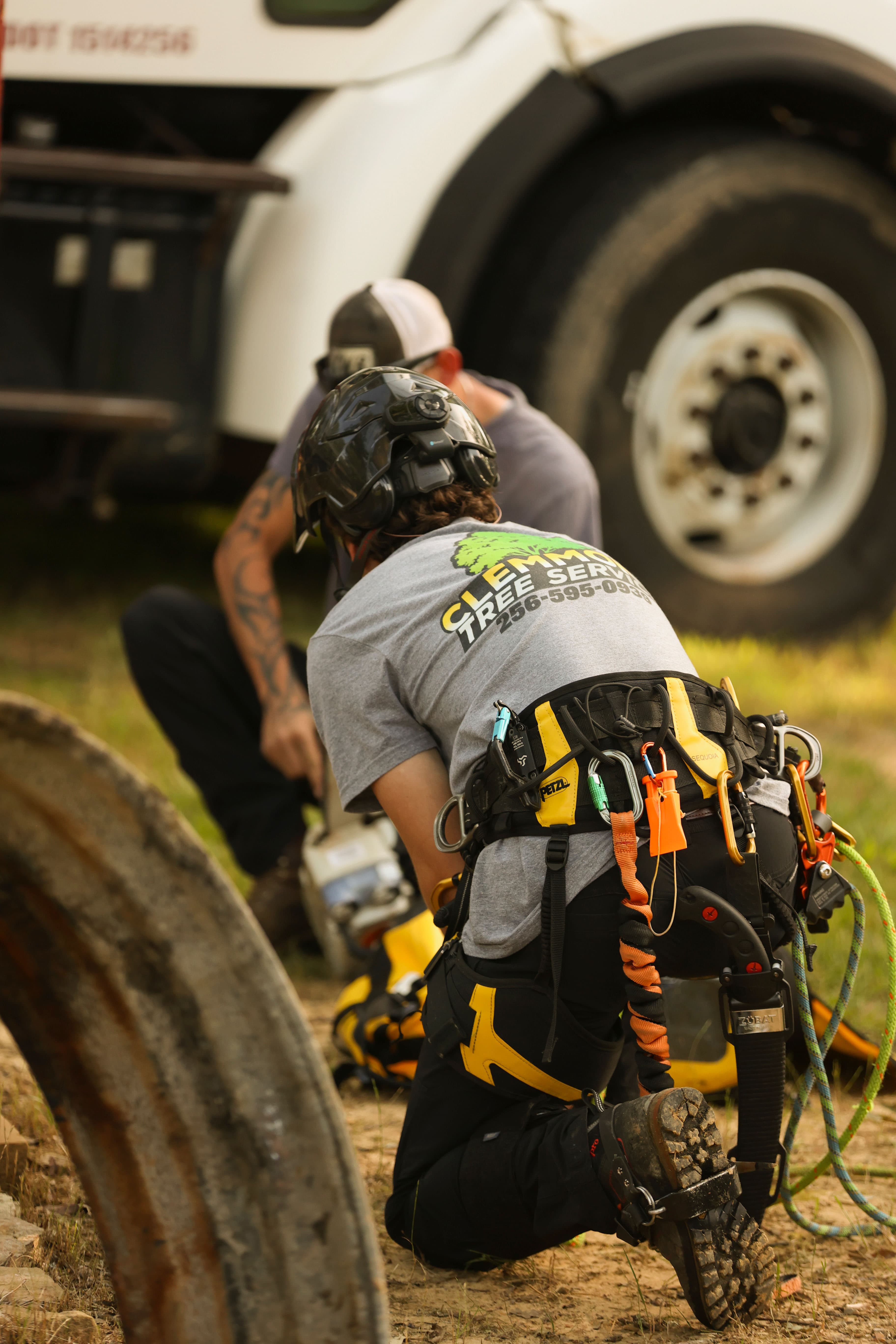 Clemmons Tree Service crew member kneeling at the truck, prepping climbing and cutting gear